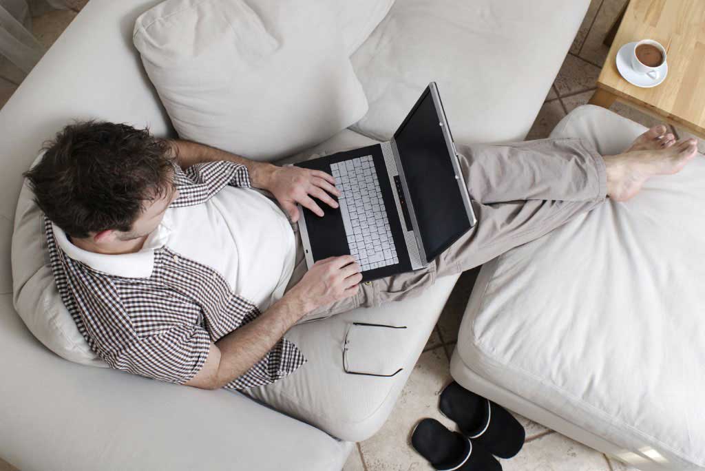Man sitting on sofa with laptop on his lap